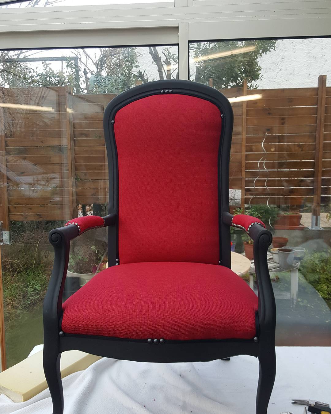 Fauteuil de style Louis XV restauré en noir mat et tissu rouge vif avec clous de tapissier argentés.