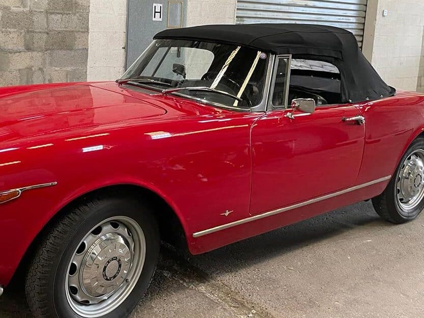 Alfa Romeo Giulia GTC rouge décapotable avec toit souple noir et finitions chromées dans un garage.