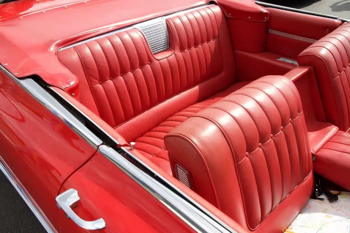 Intérieur en cuir rouge d’une voiture classique avec une sellerie luxueuse, idéalement réalisée par des artisans sellier à Bordeaux.