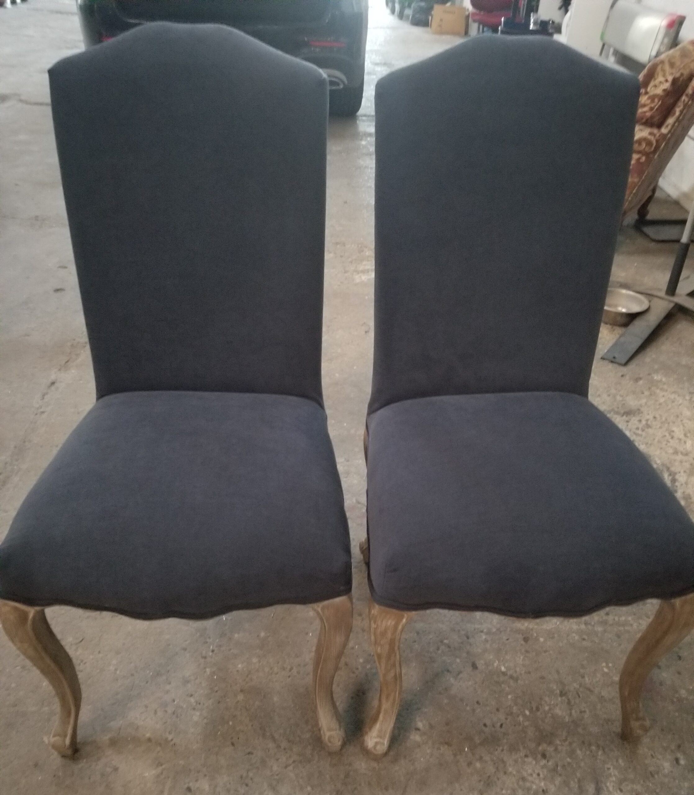 Deux chaises de salle à manger rembourrées gris foncé avec pieds en bois clair galbés de style Louis XV.