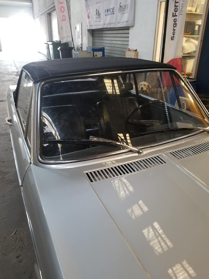 BMW 2002 Baur cabriolet grise avec capote noire dans un atelier de restauration automobile.