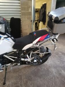 Moto BMW GS avec selle Rallye tricolore, supports de valises et top case en aluminium dans un garage.